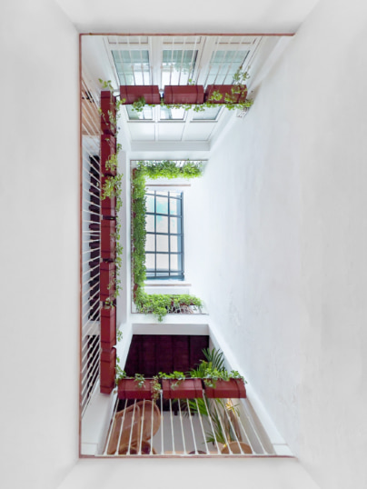 Blick von oben auf einen traditionellen andalusischen Innenhof mit Pflanzen auf den Balkonen.